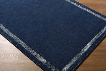Close up of the hand-tufted Tufape Modern Minimalist Area Rug. Navy blue wool with a striped border. Contemporary style. Corner