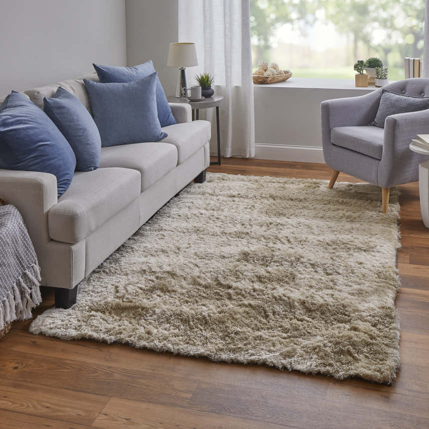 Living room scene with a Feizy Indochine Modern Solid Tan/Taupe Area Rug, sofa with blue pillows, and gray armchair. Roomscene-Rectangle