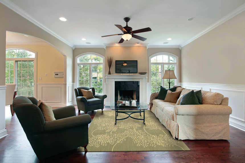 Living room scene with a Nourison Capri Sage Floral rug, sofa, chairs, fireplace, and dark wood floors.
