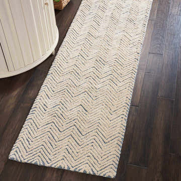 Close-up of a Nourison Deco Mod Light Blue Ivory runner rug with a modern zigzag pattern on dark wood floors.