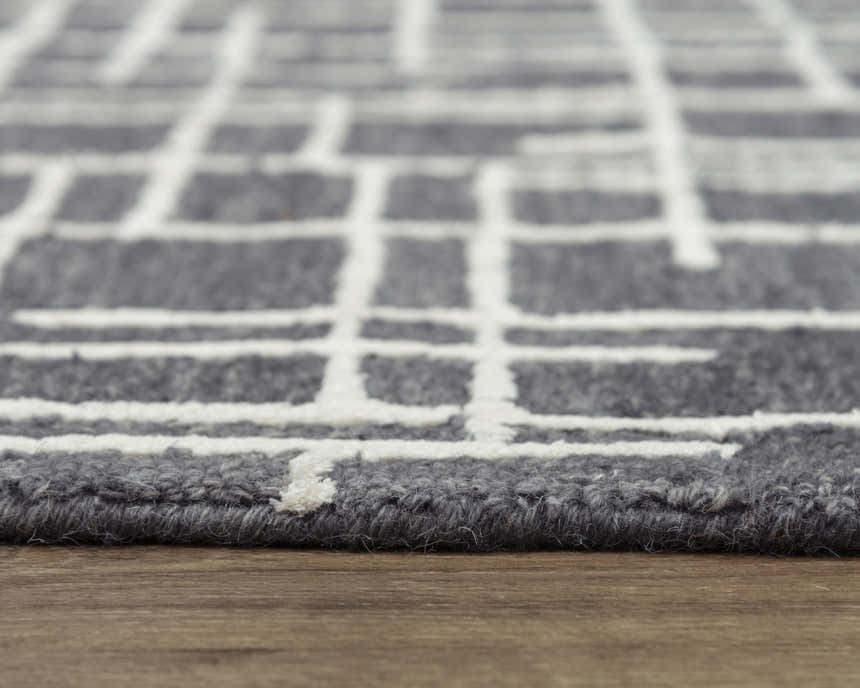 Close-up of the gray Rizzy JZZ971 area rug showing its ivory geometric pattern and hand-tufted wool texture. Pile