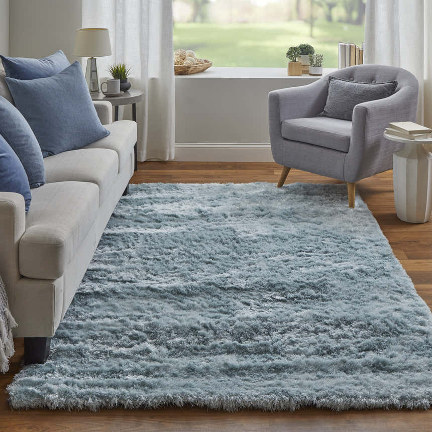 Living room scene with a Feizy Indochine blue and silver rug, sofa with blue pillows, and gray armchair. Roomscene-Rectangle