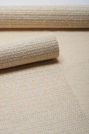 Close-up of rolled Nourison ShiftLoc Non-slip Pad Area Rug in chestnut, showing texture and machine-made construction.