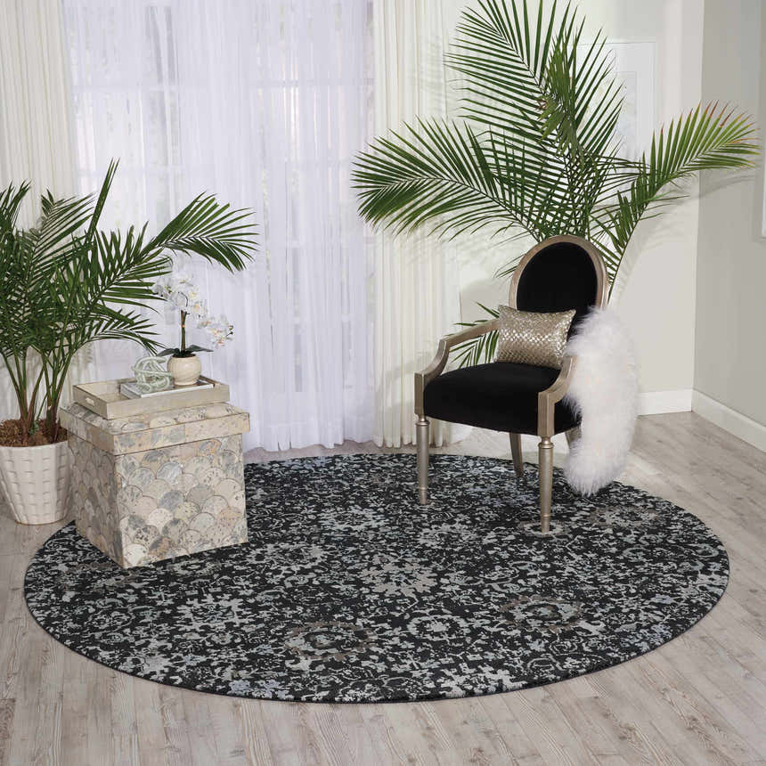 Living room scene with round Nourison Twilight Onyx Persian rug, black chair, plants, and white curtains.
