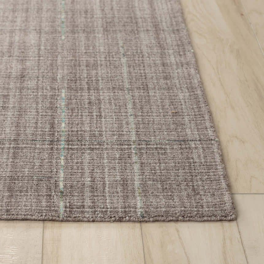 Close-up of the hand-loomed Rizzy KIK691 area rug. Gray, ivory, and blue wool and tencel blend with a subtle striped pattern. Corner
