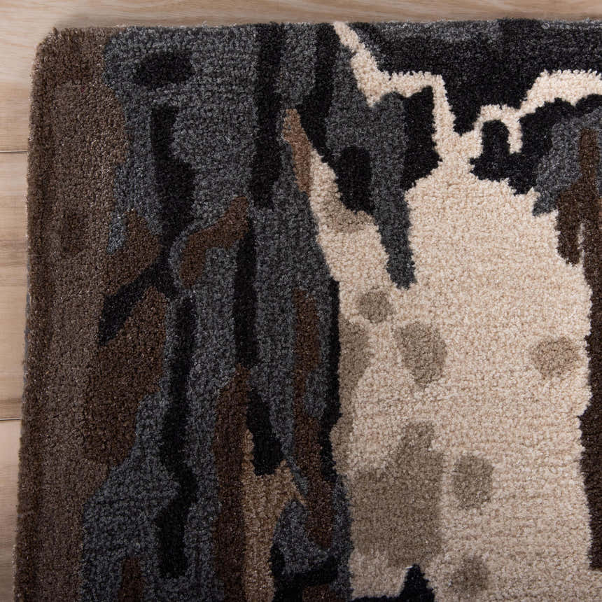 Close-up of Rizzy KIN533 area rug showing beige, charcoal, brown, and ivory abstract pattern and hand-tufted wool texture. Corner