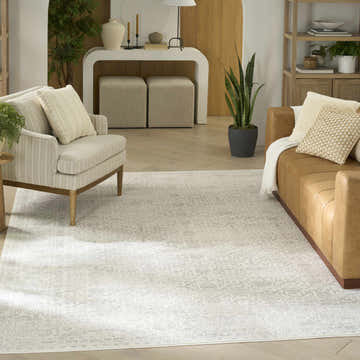 Living room scene with a Nourison Grace Grey Vintage Area Rug, leather sofa, and neutral armchair.