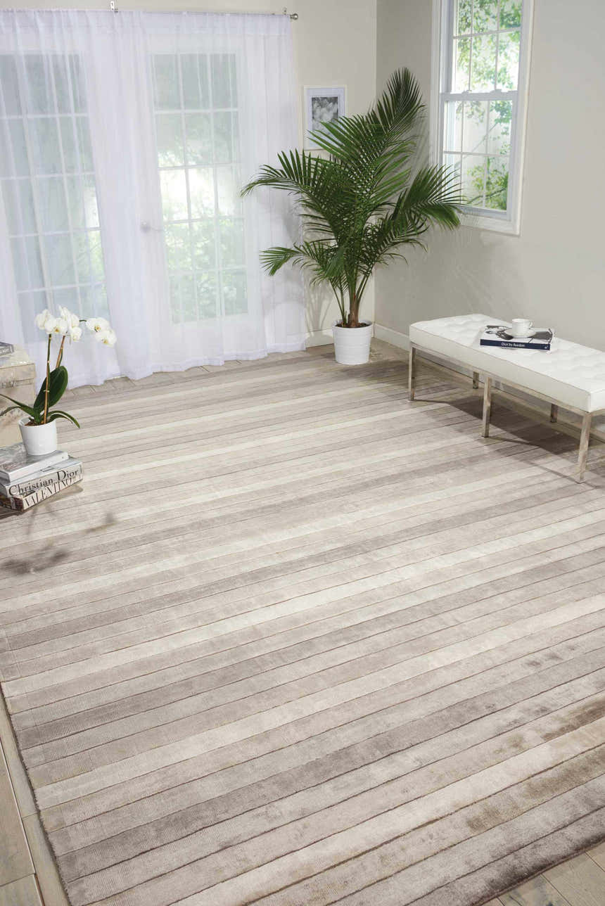 Bright living room with a Nourison Aura Silver Shadow rug, white bench, and sheer curtains.