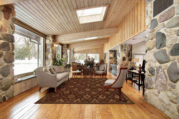 Sunroom with stone walls featuring Nourison Regal Chocolate Persian rug, sofa, and wood floors.