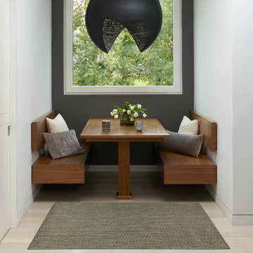Modern dining nook with wood benches and a green Nourison Horizon Indoor/Outdoor Area Rug.