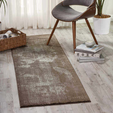 Entryway scene with a Nourison Karma Ash Vintage runner rug, gray chair, and light wood floors.