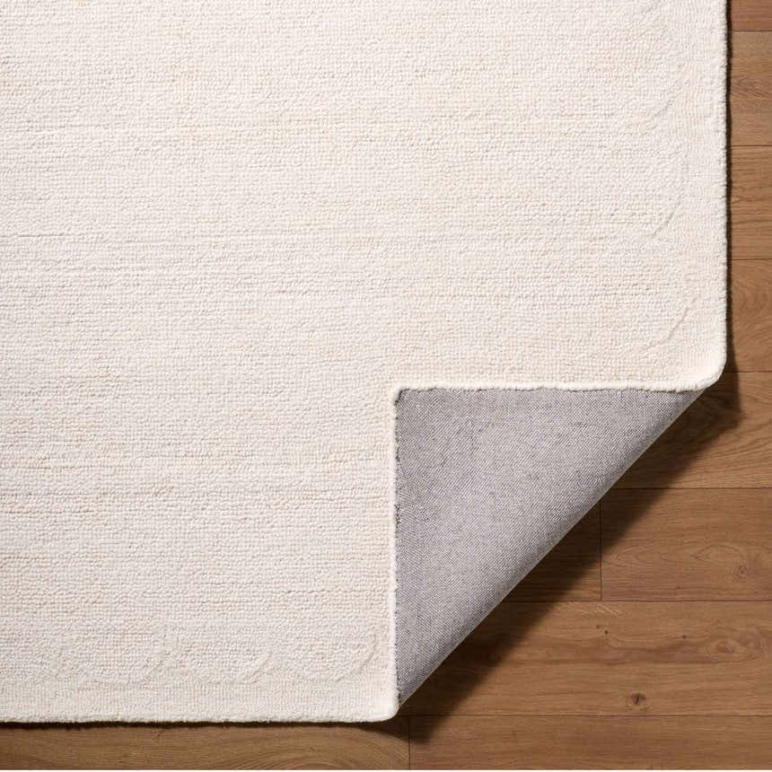 Close up of the hand tufted Kazuto Area Rug in cream wool showing texture and backing. Fold