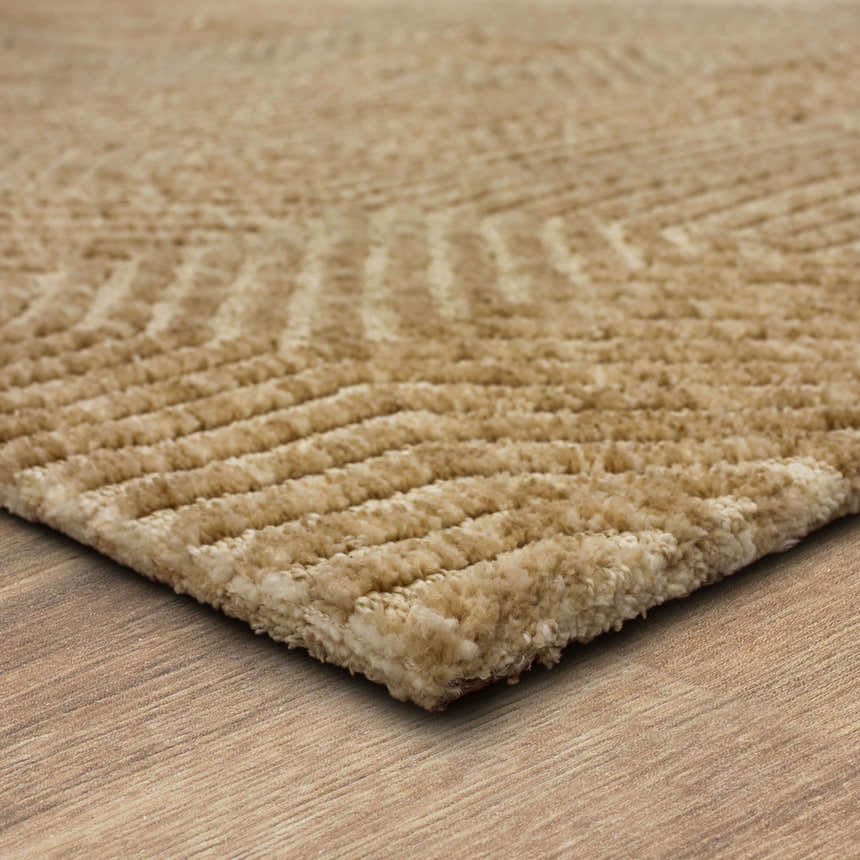 Close-up of the tan Karastan Lost City Khaki Area Rug showing its geometric pattern and soft, textured cotton and polyester material. Corner