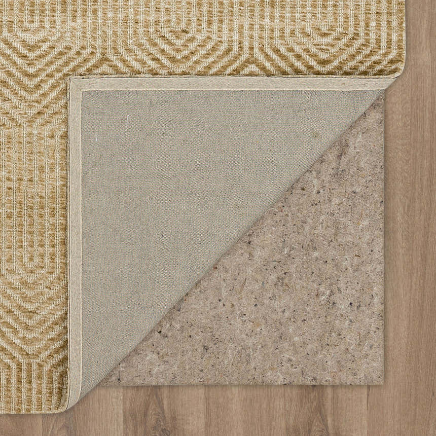 Close-up of Karastan Lost City Khaki Area Rug showing tan geometric pattern, canvas backing, and rug pad on wood floor. Back