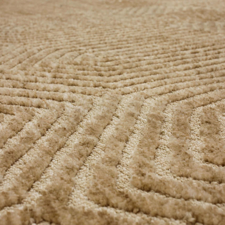 Close-up of the Karastan Lost City Khaki Area Rug featuring a geometric pattern and soft, textured tan fibers. Texture
