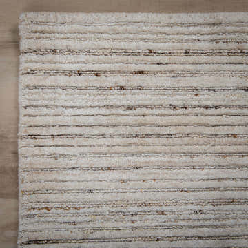 Close-up of the hand-loomed Rizzy LUX704 area rug. Beige and ivory wool rug with a casual, solid, horizontal striped design. Corner