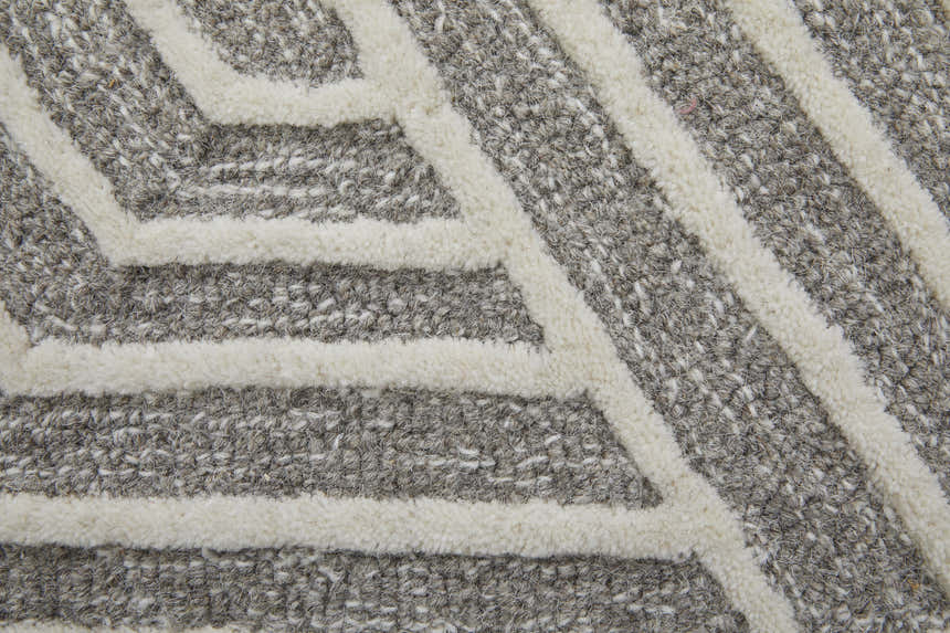 Close-up of Feizy Lytton rug showing gray wool texture and ivory geometric pattern. Hand-tufted rug detail. Texture
