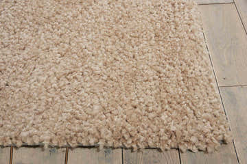 Close-up of a plush, seed-colored Calvin Klein Puli shag rug showing its texture on a light wood floor.