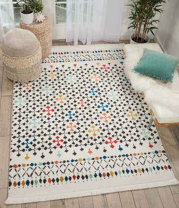 Living room scene with a Nourison Kamala White Bohemian rug, pouf, and white bench.