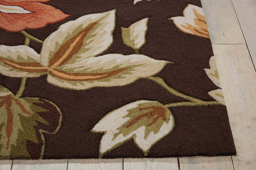 Close-up of the Nourison Fantasy Chocolate rug. Brown rug with a floral pattern in cream, green, and orange. Handmade texture.