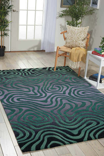 Living room scene with Nourison Contour Smoke/Teal rug. Colorful, swirl pattern in gray, teal, and black on wood floor.