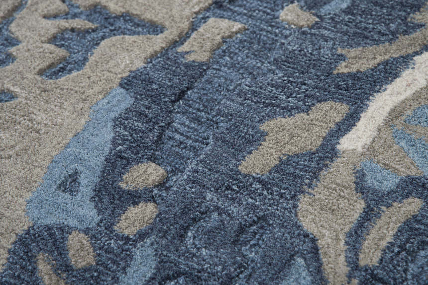 Close-up of the hand-tufted Rizzy MO867A area rug. Features a contemporary beige, gray, and navy abstract pattern. Wool texture. Texture