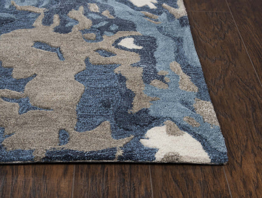 Close-up of the hand-tufted Rizzy MO867A area rug. Beige, gray, navy, and taupe abstract pattern on a wool rug. Corner