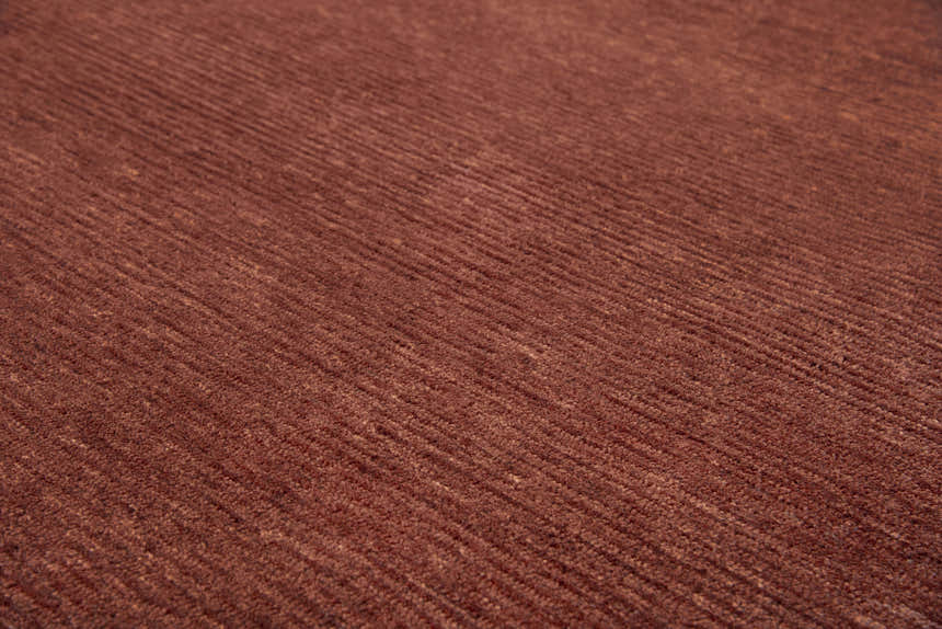 Close up of the hand-tufted Rizzy MPK101 area rug. The rug is dark red and rust with a casual, solid design. Texture