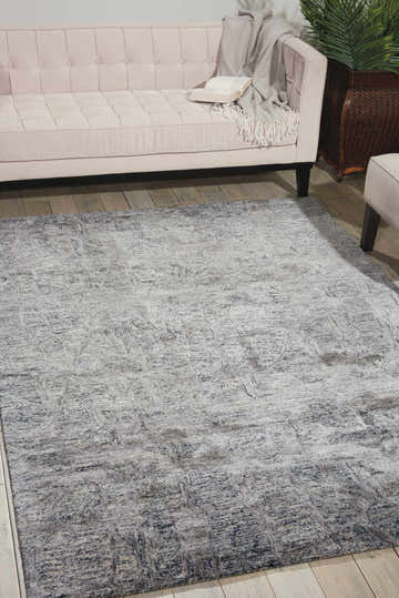 Living room scene with a Nourison Gemstone Hematite rug, light pink sofa, wood floors, and a cozy, modern feel.