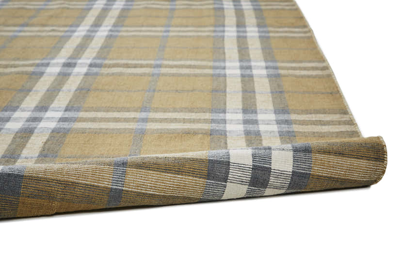 Close-up of the hand-woven Feizy Crosby Area Rug. Gold, blue, and white plaid design. Transitional style. Fold