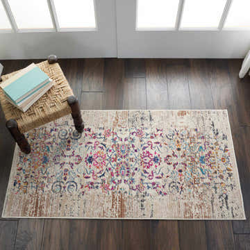 Entryway with Nourison Vintage Kashan Ivory rug, floral pattern, chestnut accents, on dark wood floor, chair with books.