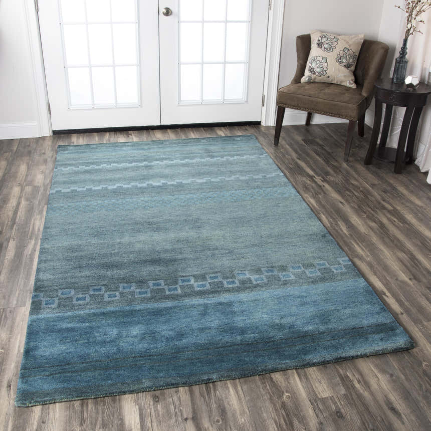Entryway with blue Rizzy MV3161 area rug, wood floors, white doors, and brown accent chair. Farmhouse style. Roomscene-Rectangle