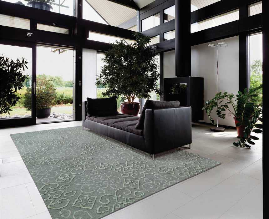Modern living room with black sofa and Nourison Ambrose Slate Indoor Area Rug. Taupe wool rug with geometric pattern.