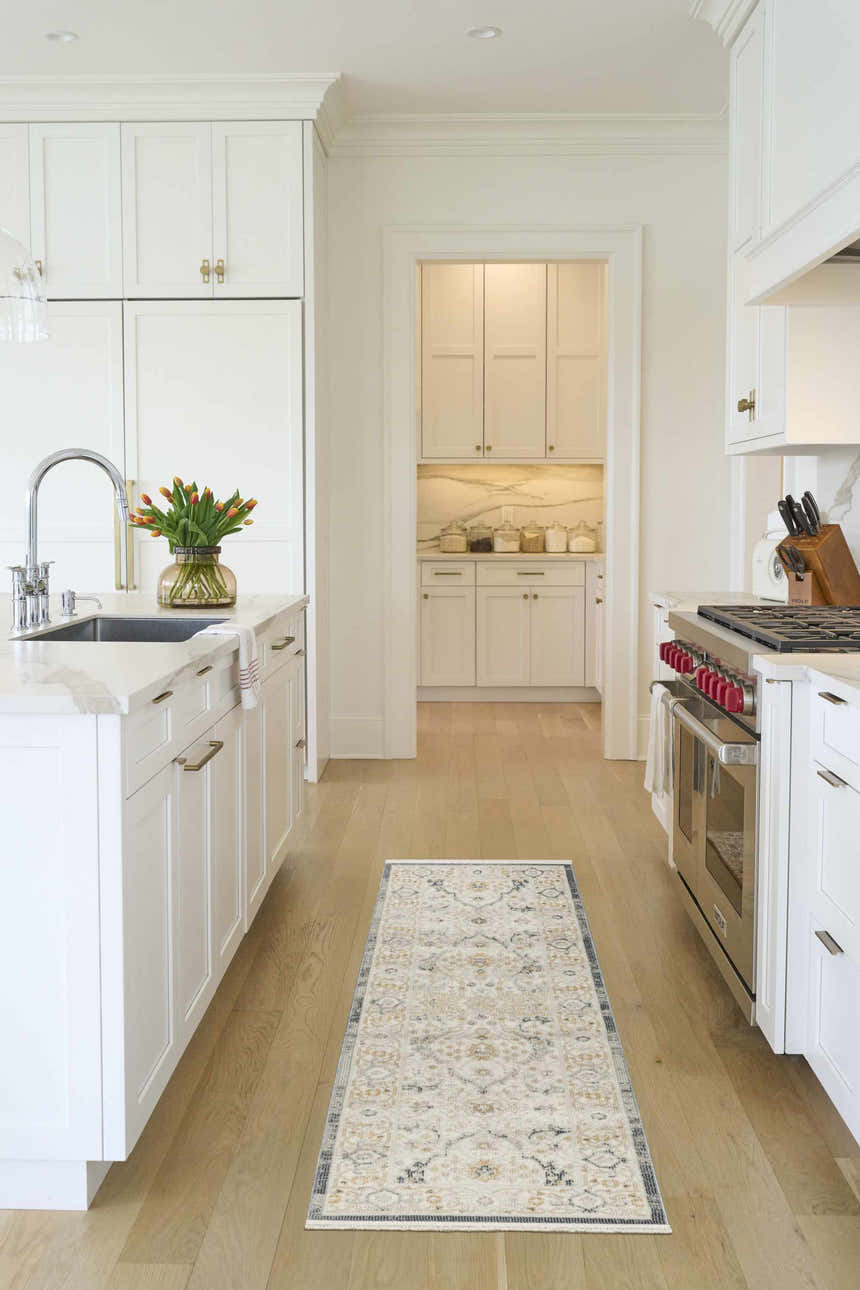 Light blue Nourison Pardis vintage runner rug in a bright, modern white kitchen with wood floors.