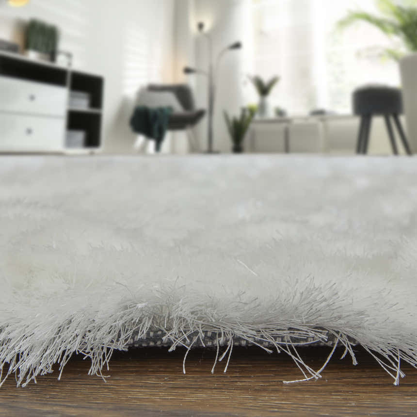 Close-up of the plush texture of a white Feizy Indochine area rug in a modern living room setting. Pile