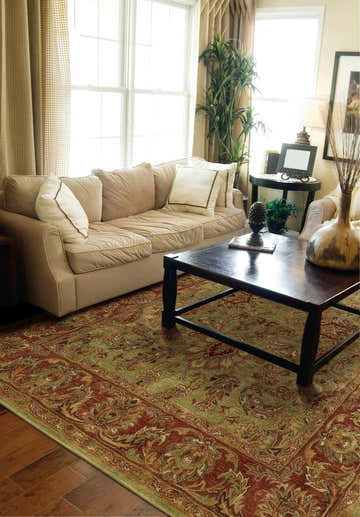 Living room scene with a Nourison Jaipur Olive Persian rug, beige sofa, and dark wood coffee table.