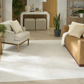 Living room scene with a Nourison Grace Ivory Light Grey Vintage Area Rug, tan leather sofa, and striped armchair.