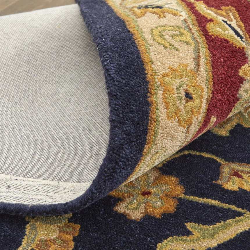 Close-up of the Feizy Wagner Traditional Oriental Rug showing blue, red, and gold floral details and hand-tufted texture. Fold