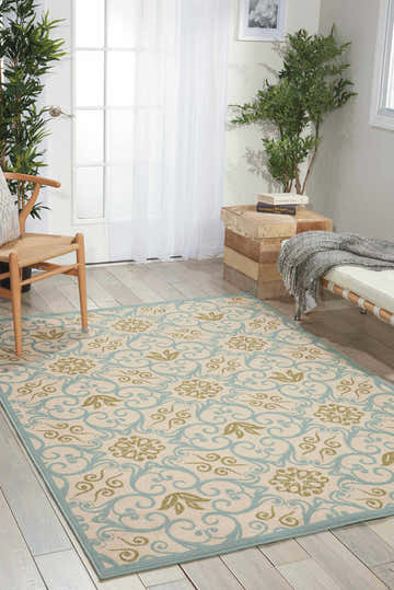 Light-filled room with a Nourison Caribbean Ivory Blue rug, wood floors, chair, and bench. Serene, contemporary style.