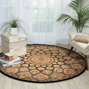 Bright living room with round Nourison 2000 Slate Persian rug, taupe floral pattern, white chair, and potted plants.
