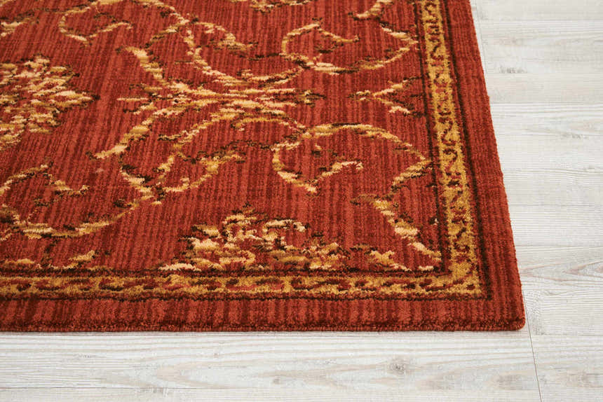 Close-up of the persimmon Nourison Radiant Impression rug. Vintage style with floral patterns and a textured wool pile.