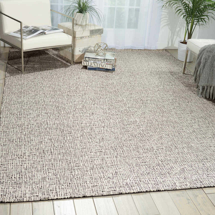 Modern living room with a Nourison Starlight Midnight rug, white chairs, and light wood floors.