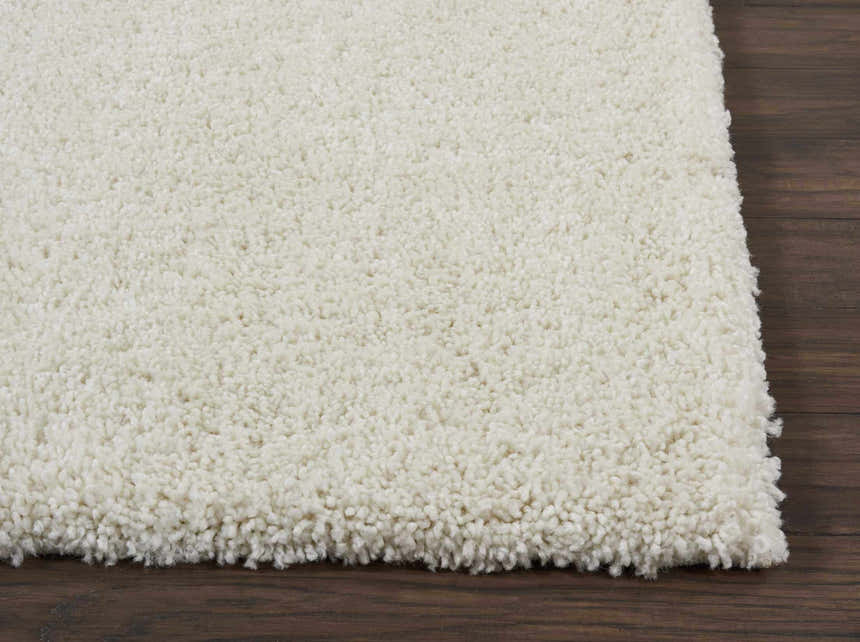 Close-up of the plush, ivory texture of the Nourison Malibu Shag rug on dark wood flooring.