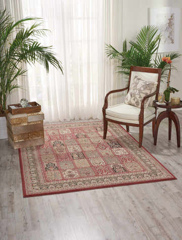Living room scene with a Nourison Ararat Burgundy Persian rug, chair, plants, and light wood floors.