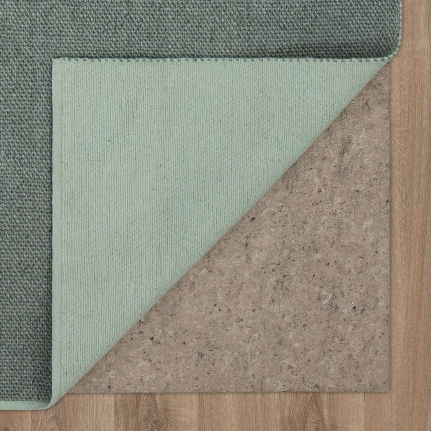 Close-up of Karastan Paloma Seaglass Area Rug showing gray green color, hand-loomed texture, and rug pad. Fold