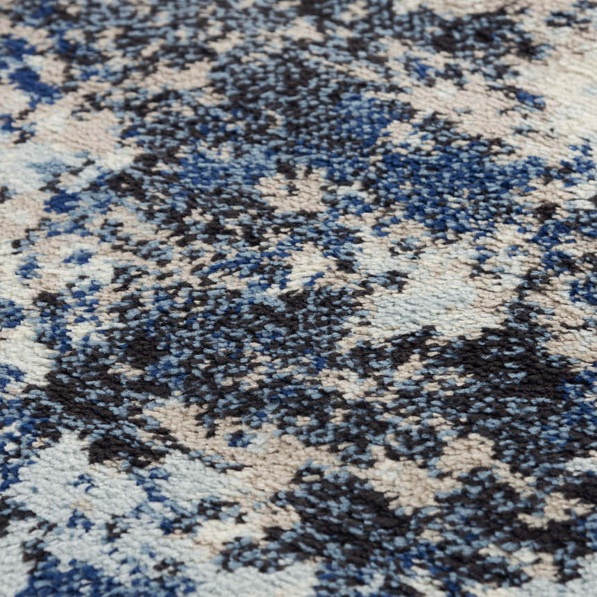 Close-up of the Rizzy PLC855 area rug. Abstract design in beige, black, blue, and ivory. Power-loomed texture. Texture