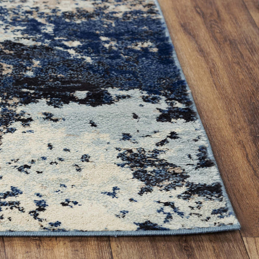 Close up of Rizzy PLC855 area rug showing abstract beige, black, and blue pattern and texture. Corner