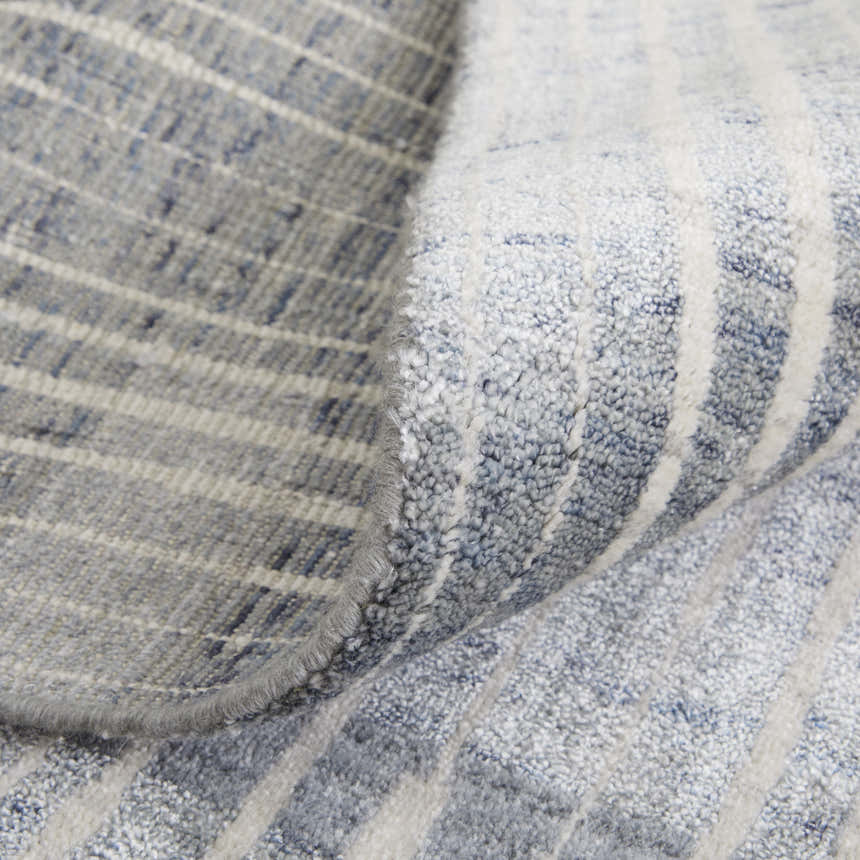 Close-up of the Feizy Eastfield Rug. Blue, gray, and ivory wool rug with a modern abstract grid pattern and distressed texture. Fold