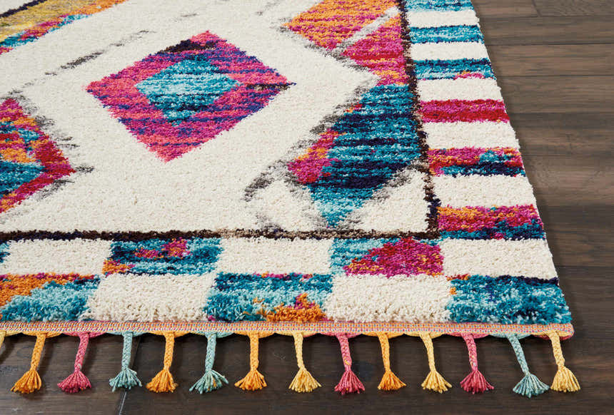 Close-up of Nourison Nomad Ivory Multicolor Tribal rug showing geometric patterns, shag texture, and colorful tassels.
