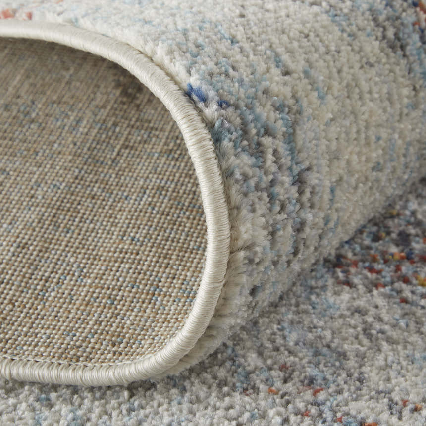 Close-up of the Feizy Edgemont rug showing its ivory, blue, and orange abstract pattern and textured weave. Fold